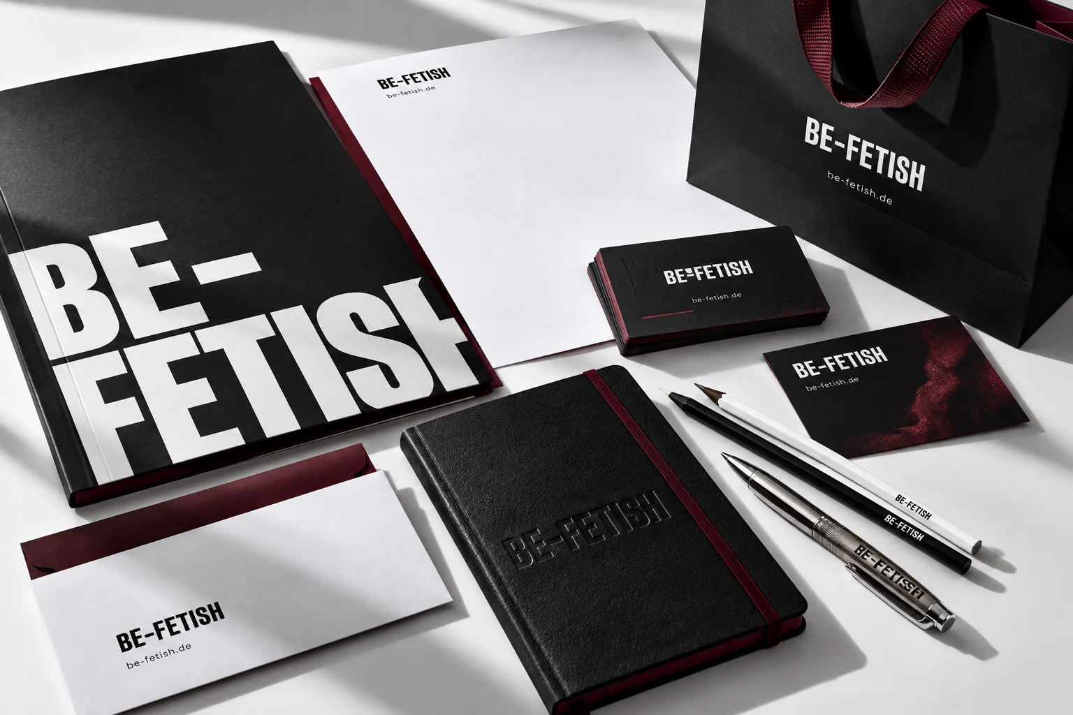Designkonzept für BE-FETISH: schwarze und weiße Geschäftsausstattung mit Mappe, Visitenkarten, Briefpapier, Umschlag, Notizbuch, Stiften und Papiertasche