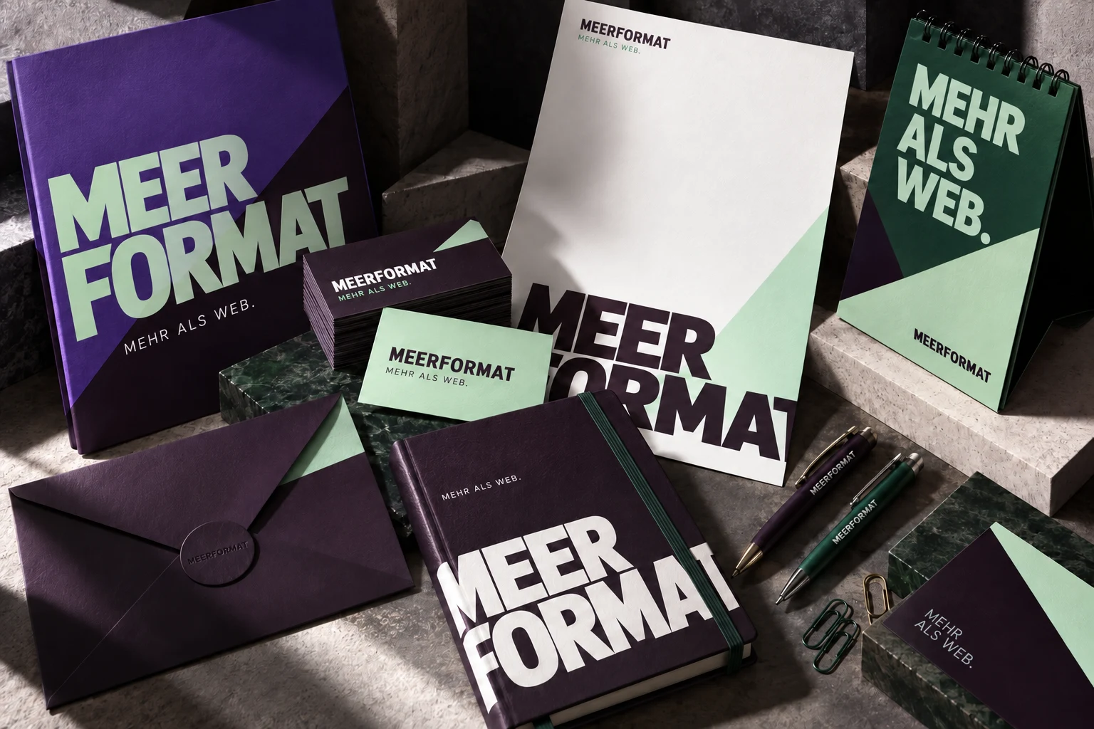 Meerformat-Gestaltungsbeispiel auf Visitenkarten, Briefpapier, Mappe, Notizbuch und Stiften